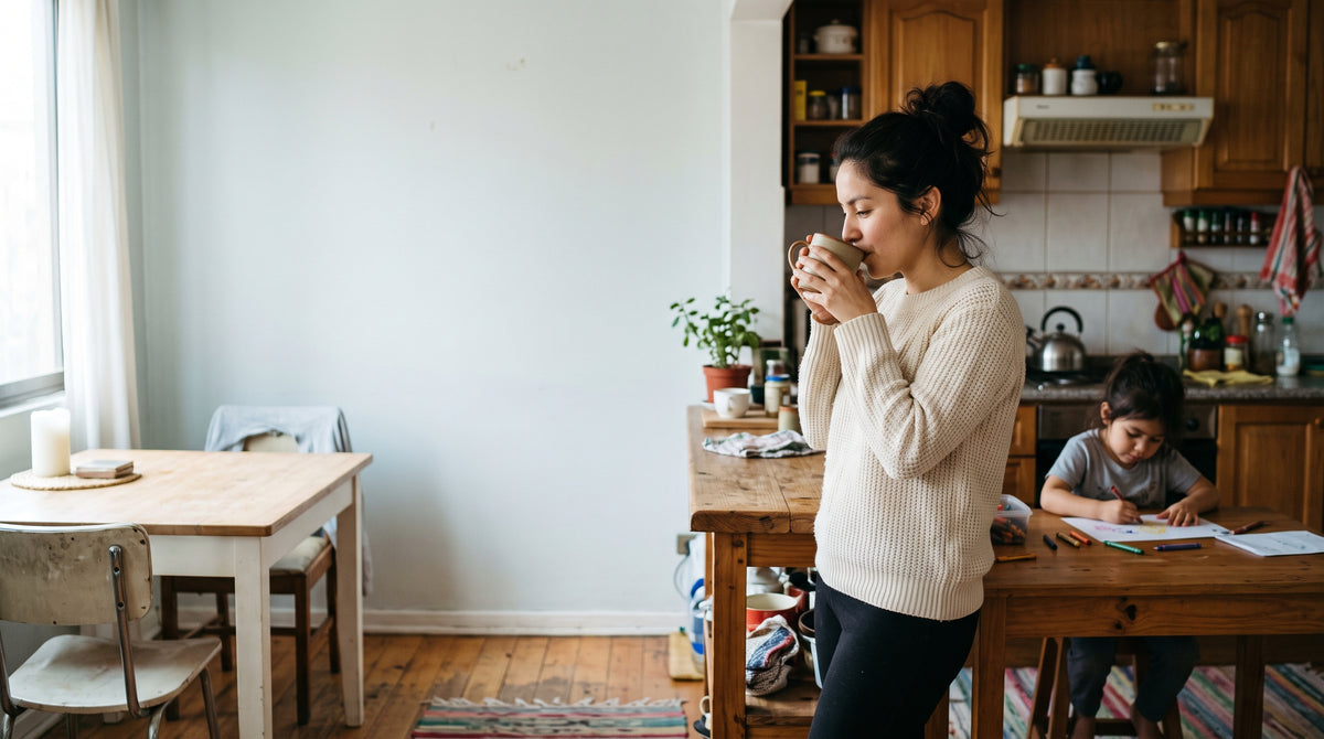 Una mama toma su cafe en la cocina mientras su hija dibuja en la mesa